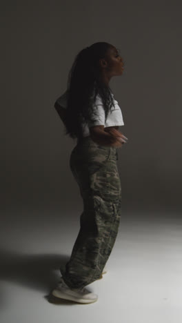 Vertical-Video-Backlit-Studio-Portrait-Shot-Of-Young-Woman-Dancing-Against-Grey-Background-4